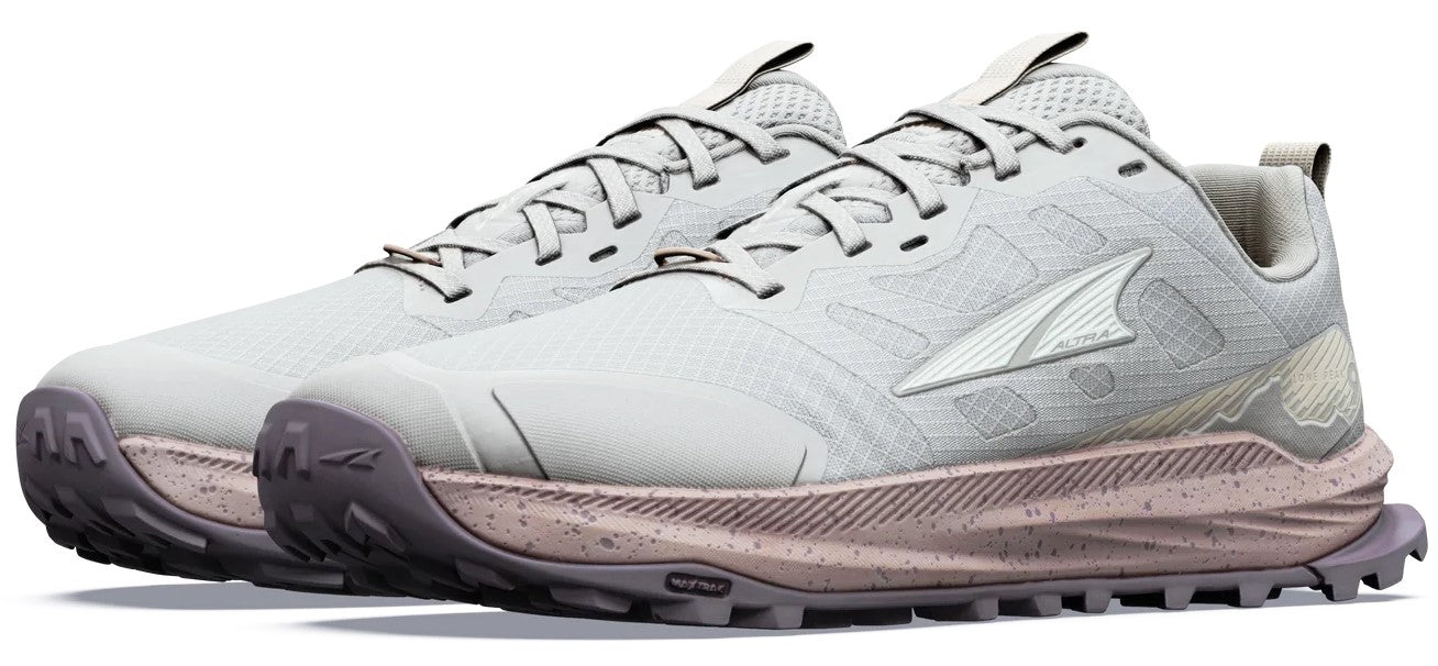 A pair of light grey, low-top trail running shoes featuring a textured, dusty rose midsole with a speckled pattern and a lugged, dark grey outsole. The shoe has a mesh upper, lacing system, and a metallic silver logo on the side.