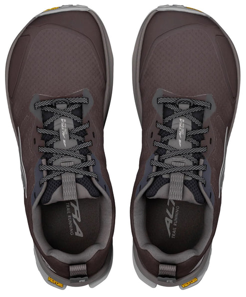 A top-down view of a pair of dark brown trail running shoes with grey laces, grey inner linings, and yellow Vibram brand logos on the heels.