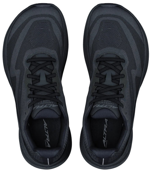 A top-down view of a pair of black, wide-toe running shoes with black laces, black mesh uppers, and the Altra Experience Flow text visible on the tongues and insoles.