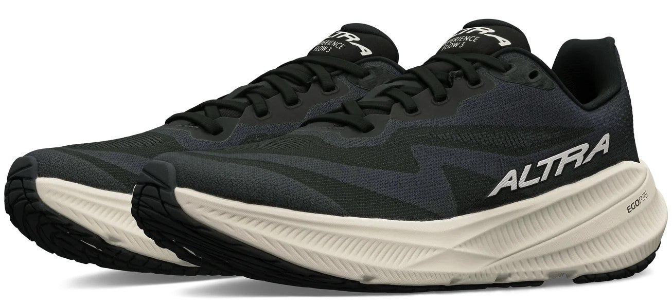 A pair of black Altra Experience Flow shoes with a thick, textured, off-white midsole and black outsoles, viewed from a slightly angled front-side perspective.