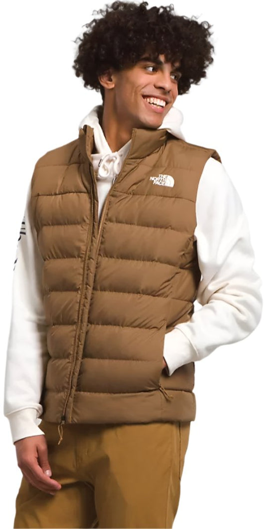 A person wearing a brown puffer vest with a zipper and pockets.