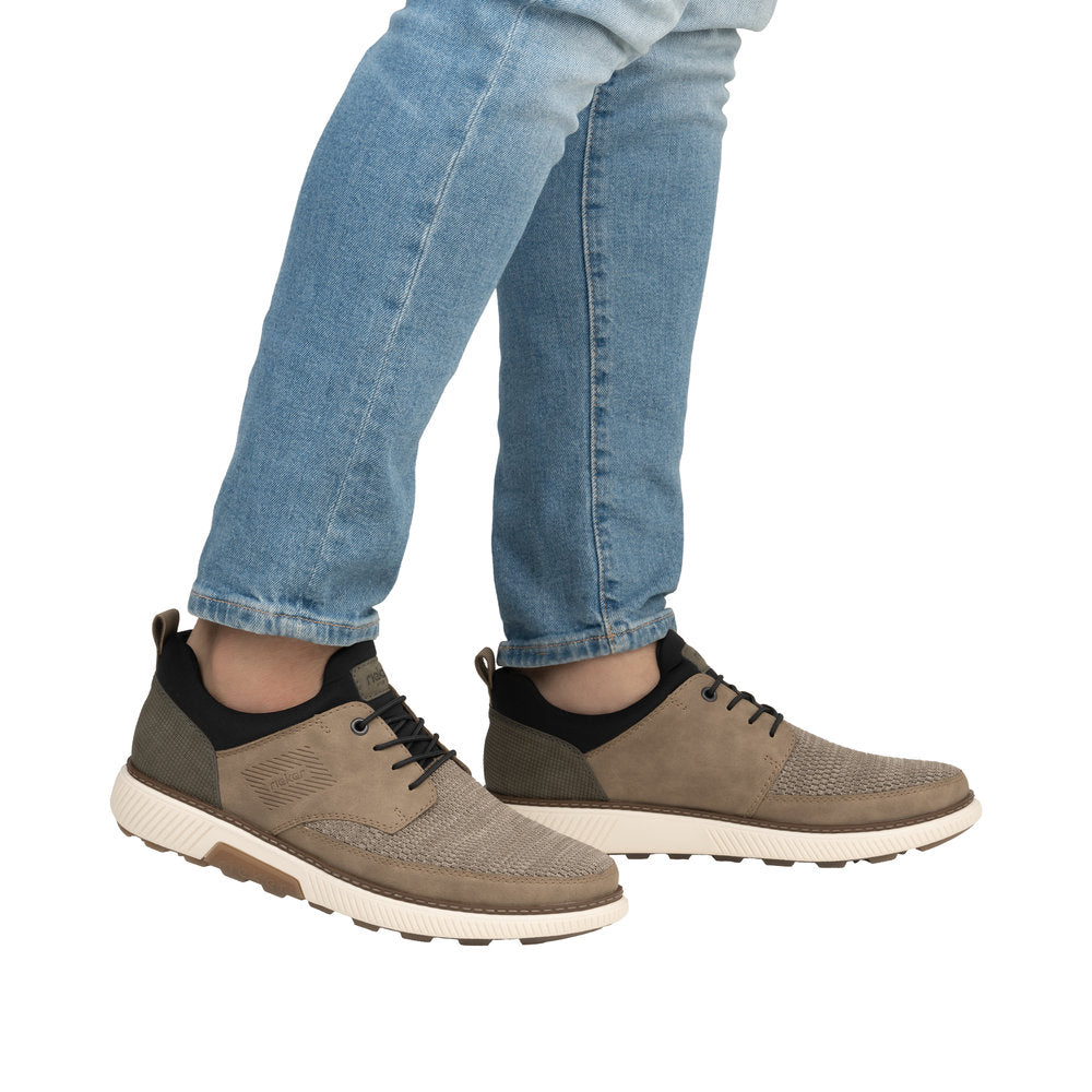 Person wearing jeans and brown casual shoes with black trim and white soles.