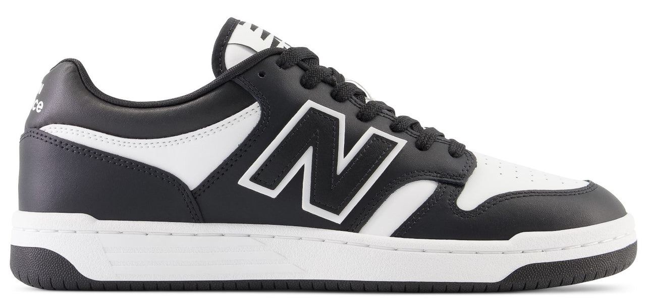 A low-top athletic shoe with black and white coloring and a New Balance logo on the side.