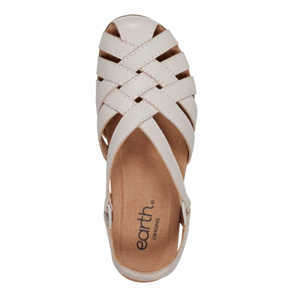 Overhead shot of a light beige sandal with interlaced straps and an ankle strap, with the text 'earth ORIGINS' on the insole.