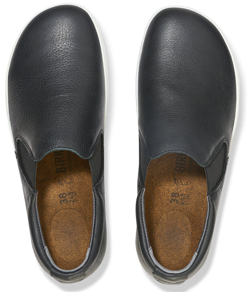 A pair of black leather slip-on shoes with cork insoles, viewed from directly above, showing size 38 stamped on the interior.