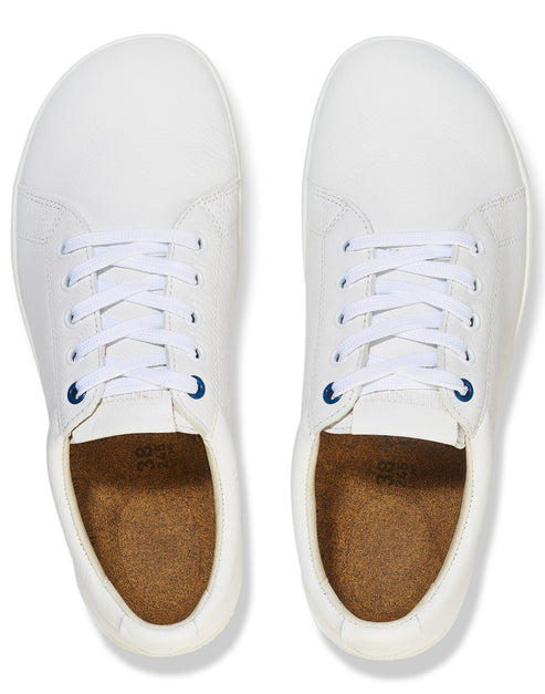 A pair of clean white sneakers viewed from directly above, featuring white laces, dark blue bottom eyelets, and tan cork-like insoles marked with the size 38.