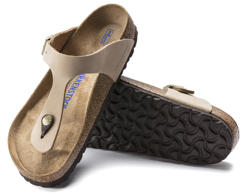 A pair of beige thong-style sandals with adjustable straps and prominent BIRKENSTOCK logo on the footbed, one sandal is turned over to show the textured sole.
