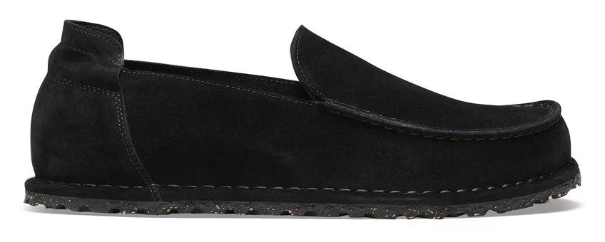 A black suede loafer-style shoe with a low heel and a thick, textured sole.