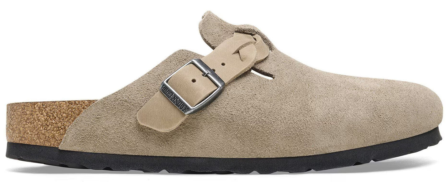 A beige suede slip-on clog with a cork footbed, a black sole, and a silver metal buckle strap across the side.