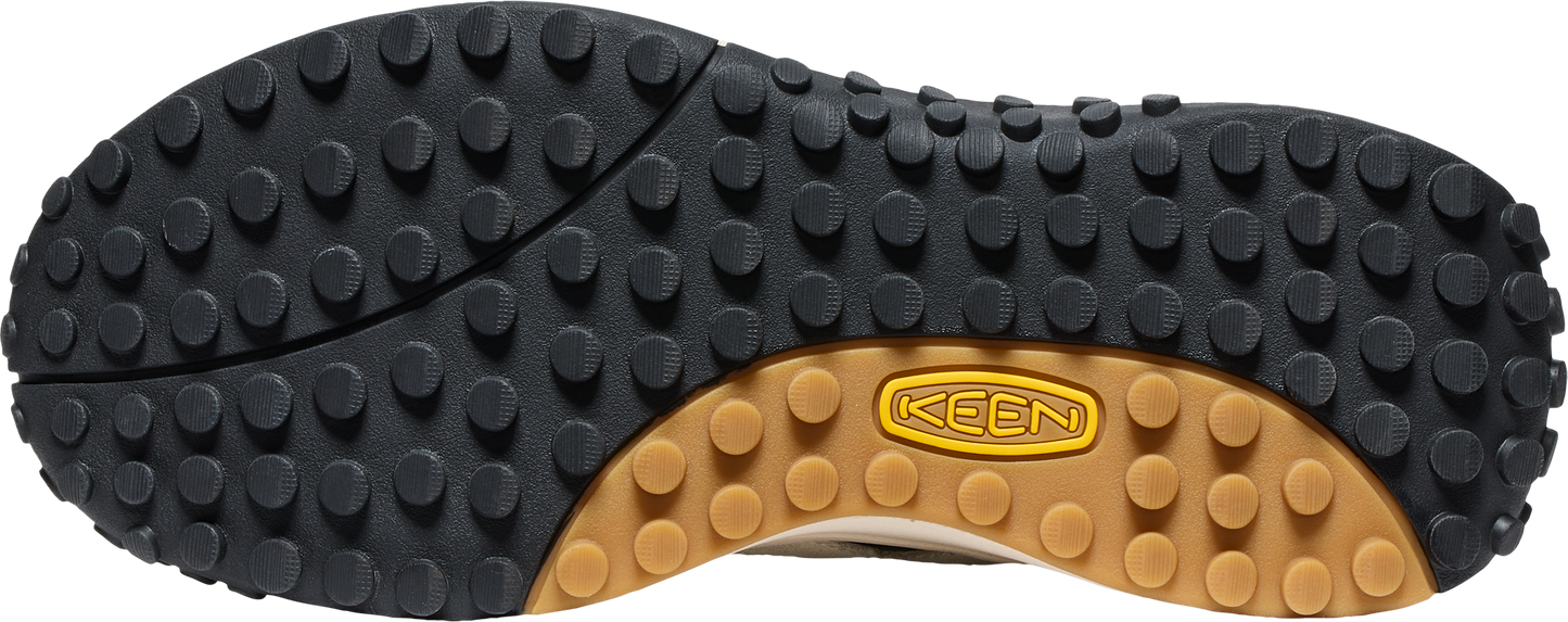 The sole of a shoe featuring a black rubber tread with small, round nubs and a brown rubber arch displaying the text "KEEN".