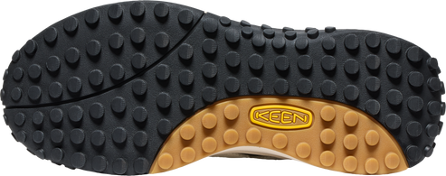 The sole of a shoe featuring a black rubber tread with small, round nubs and a brown rubber arch displaying the text "KEEN".