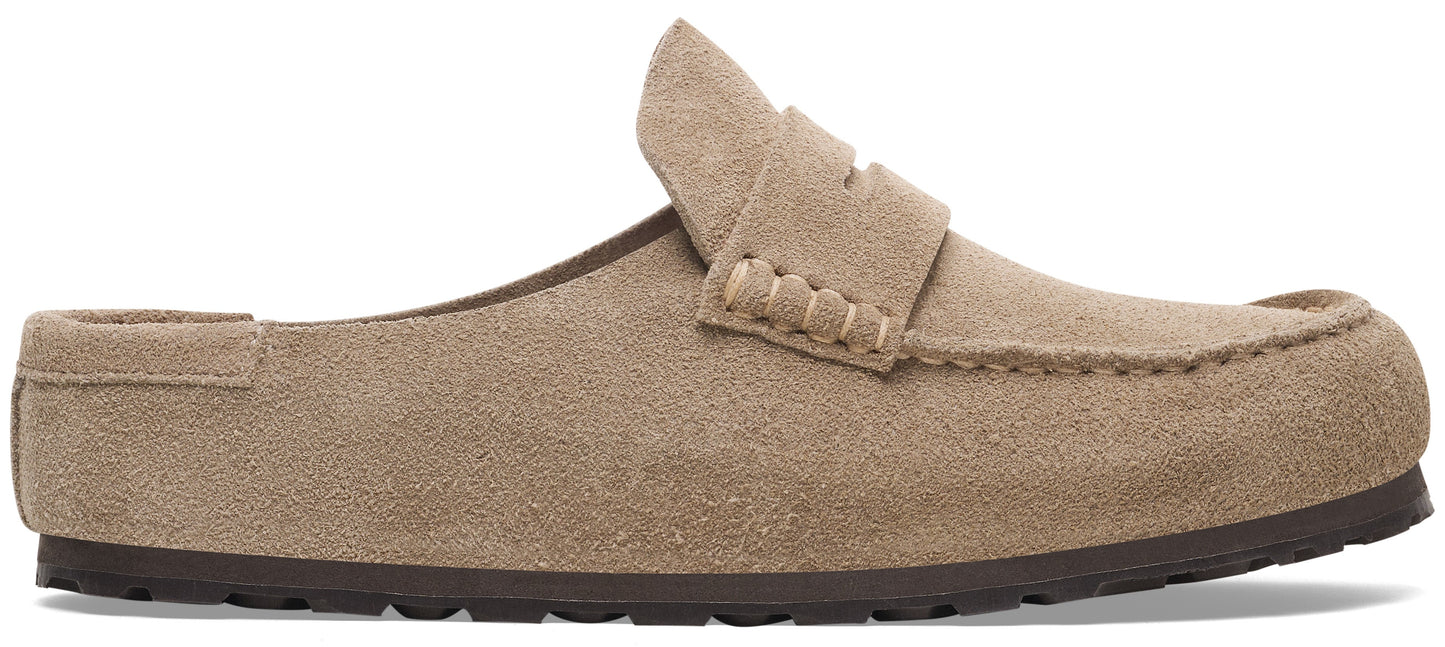A slip-on loafer mule made of light tan suede leather with a decorative strap across the vamp and a dark brown, textured rubber sole.