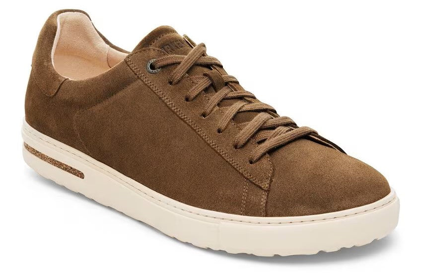 Low profile brown suede sneaker with white sole and lace-up closure.