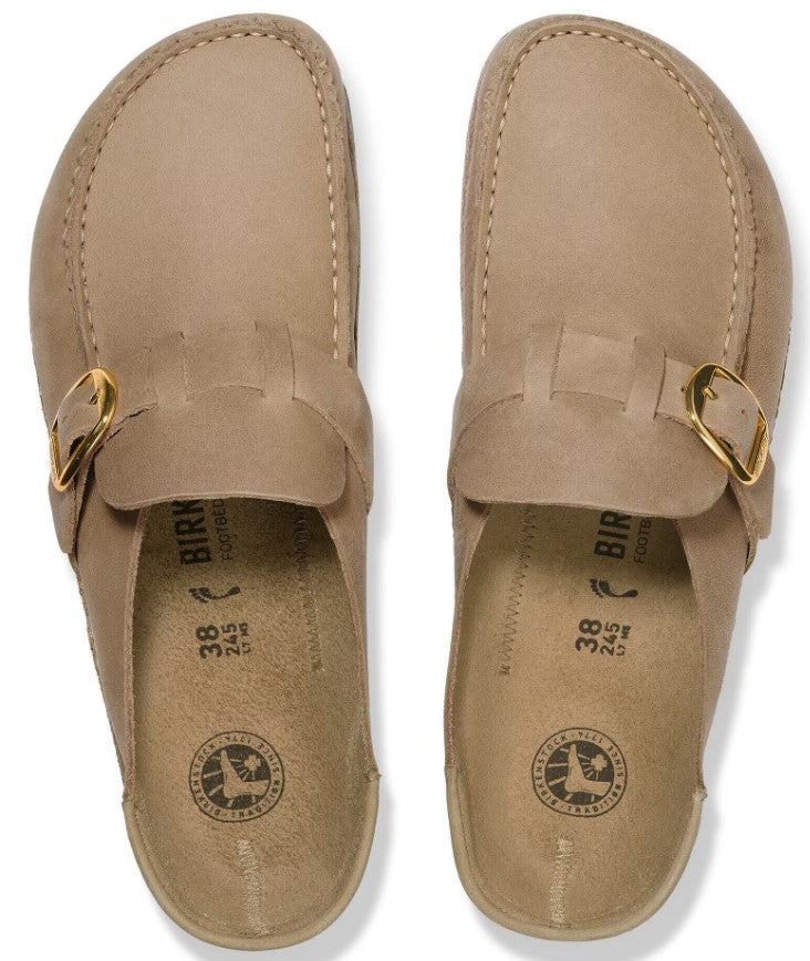 A pair of tan suede clogs, viewed from directly above, featuring a leather strap with a gold-tone metal buckle across the midfoot and molded footbeds stamped with size 38 and the BIRKENSTOCK logo.