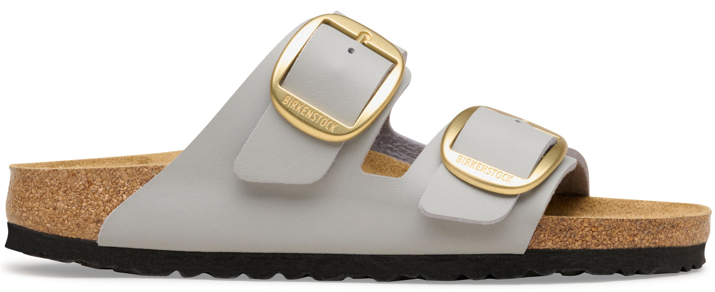 A gray sandal with two gold buckles.