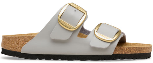 A gray sandal with two gold buckles.