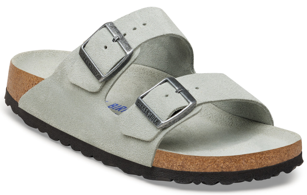 A light gray suede sandal with two adjustable straps and silver buckles.