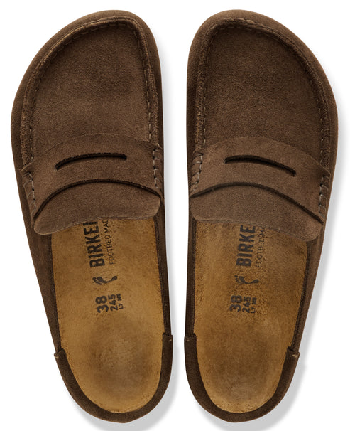 A pair of brown suede slip-on loafers, viewed from directly above, showing the cork footbeds labeled with size 38 and the text BIRKENSTOCK.