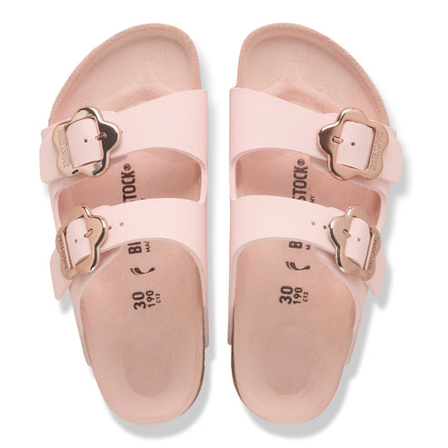 Two pink sandals with two straps and flower-shaped buckles.