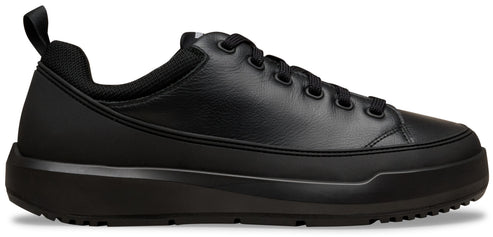 A minimalist, all-black low-top leather sneaker with a thick, matching black rubber platform sole, black laces, and a small pull tab on the heel.
