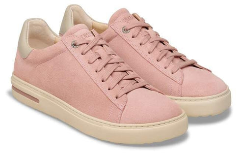 Pair of pink suede sneakers with light beige soles and gold heel accents, laced.