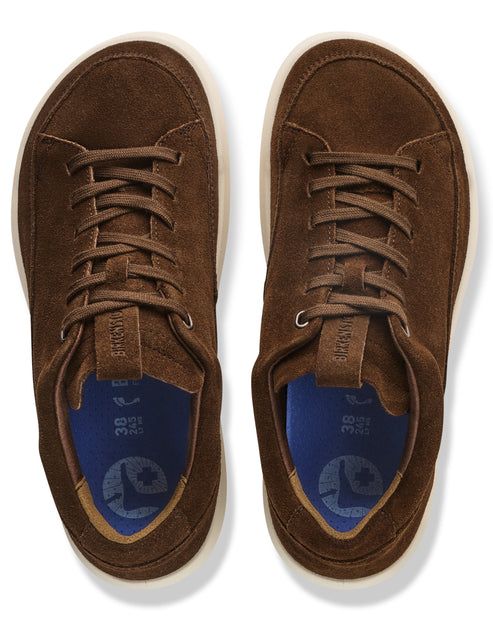 A pair of brown suede sneakers seen from a top-down view with dark blue insoles featuring a foot-shaped icon, size 38 markings, and light-colored soles.
