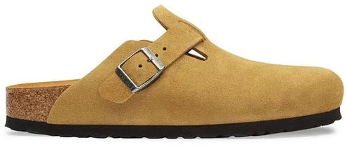 A tan suede slip-on clog with a single side strap and silver-toned metal pin buckle, featuring a cork midsole and a textured black rubber outsole.