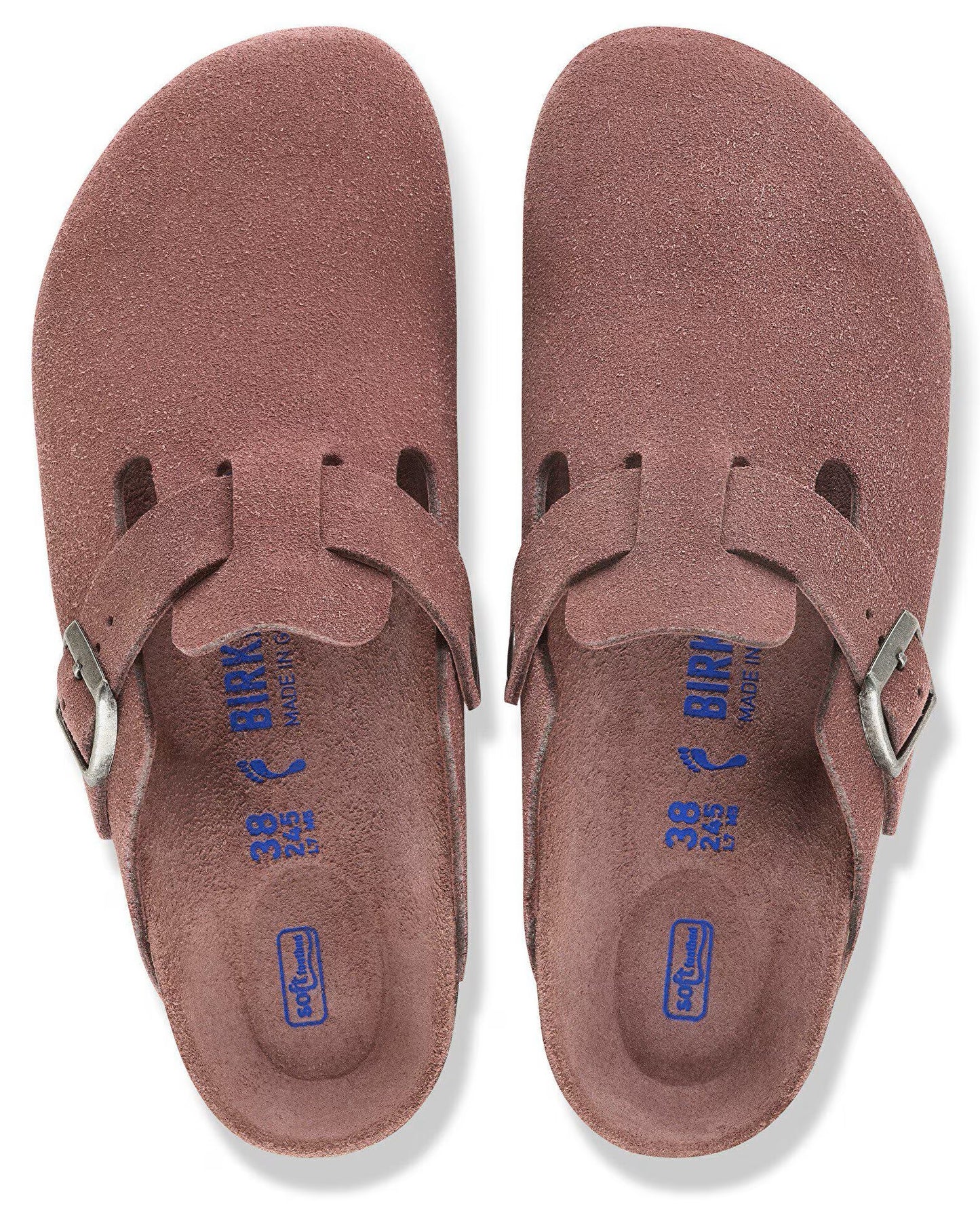 A pair of mauve, suede leather slip-on shoes with a buckled strap, a contoured footbed, and the text BIRKENSTOCK, 38, and 245 printed on the inner sole.