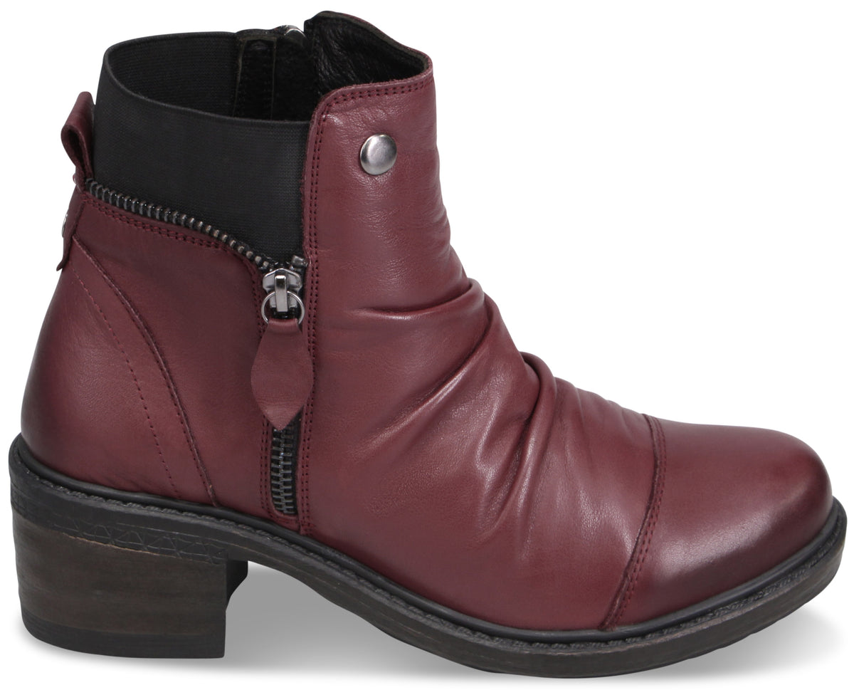 A maroon ankle boot with a slight heel, featuring a side zipper, ruched leather detail on the upper, and a silver metal accent near the ankle.