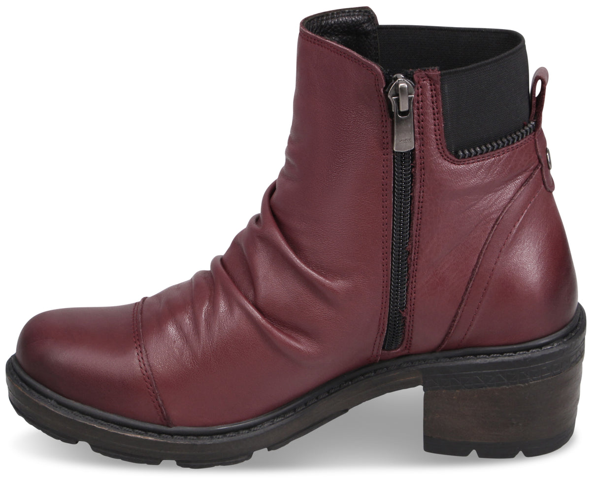 A maroon ankle boot with a pleated leather upper, a side zipper, and a black block heel with a textured lug sole.
