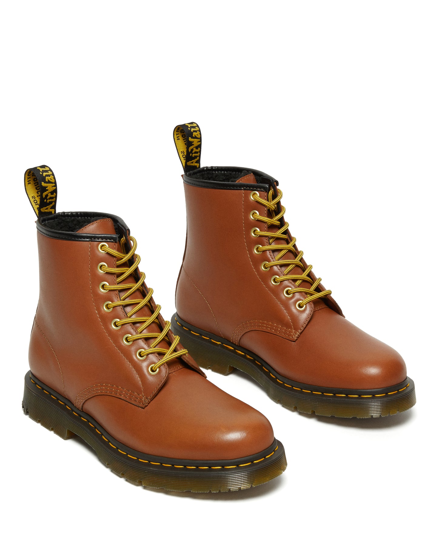 A pair of tan leather work boots with yellow laces and black soles.