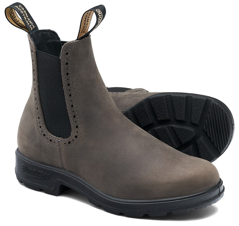 A gray leather Chelsea boot with perforated detail along the elastic side panel, featuring black branded pull tabs and a thick, black, lugged rubber sole.