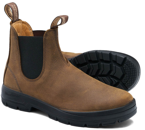 A brown leather Chelsea boot with black elastic side panels and thick black lugged rubber soles, featuring two pull tabs at the collar with text that reads 'TASMANIA AUSTRALIA' and 'BLUNDSTONE'.
