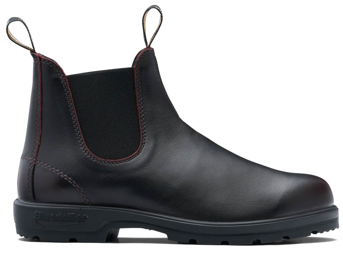 A dark brown leather Chelsea boot with dual pull tabs, elastic side panels, contrast red stitching along the leather seams, and a thick, lugged black rubber sole with the word Blundstone embossed on the heel.