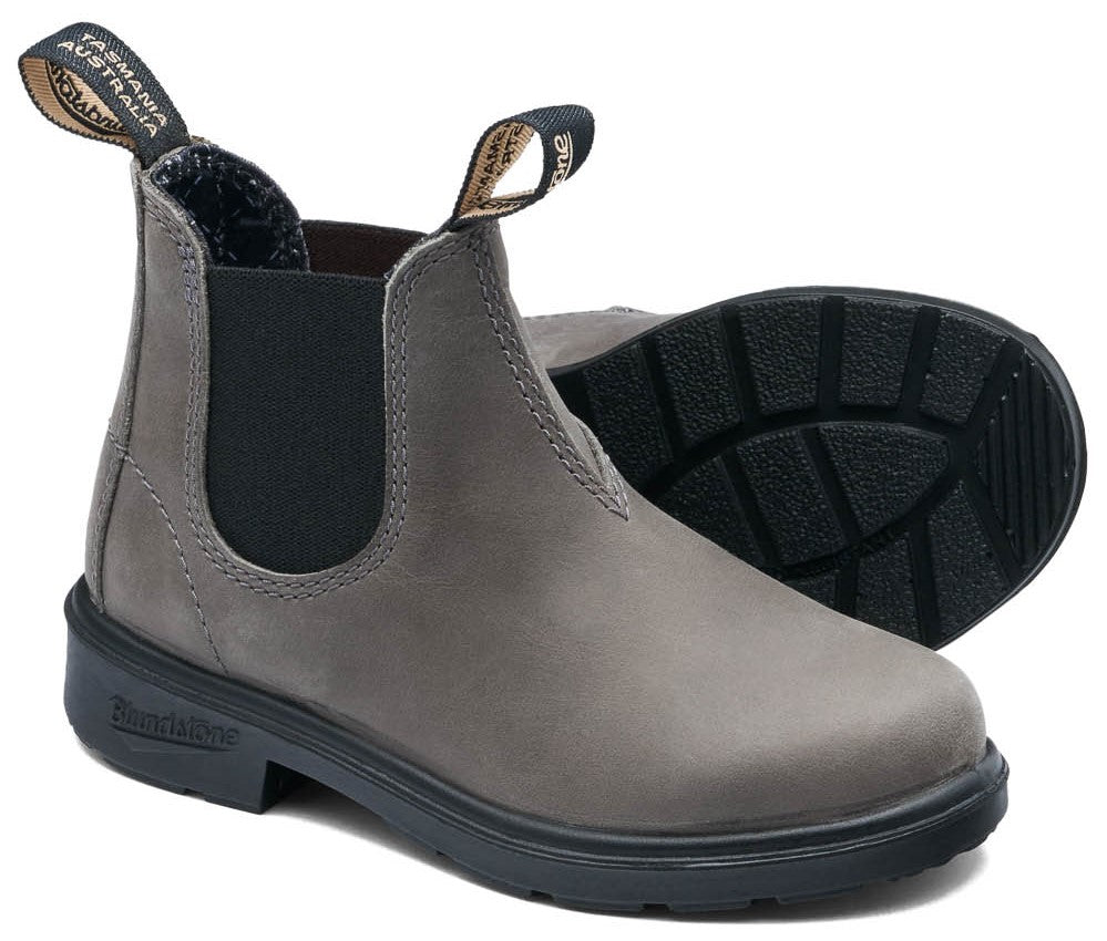 A gray leather Chelsea boot with black elastic side panels, black rubber lug soles, and two pull tabs on the collar that read "Tasmania Australia" and "Blundstone".