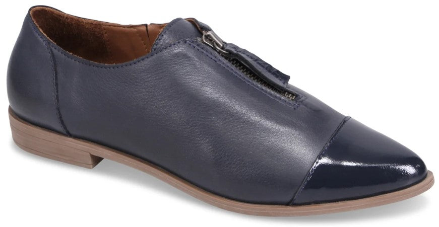 A navy blue leather women's low-heeled oxford shoe featuring a front zipper closure and a glossy, patent leather-like pointed toe cap on a tan sole.