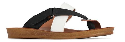 A sandal with a tan sole and a black and white strap design.