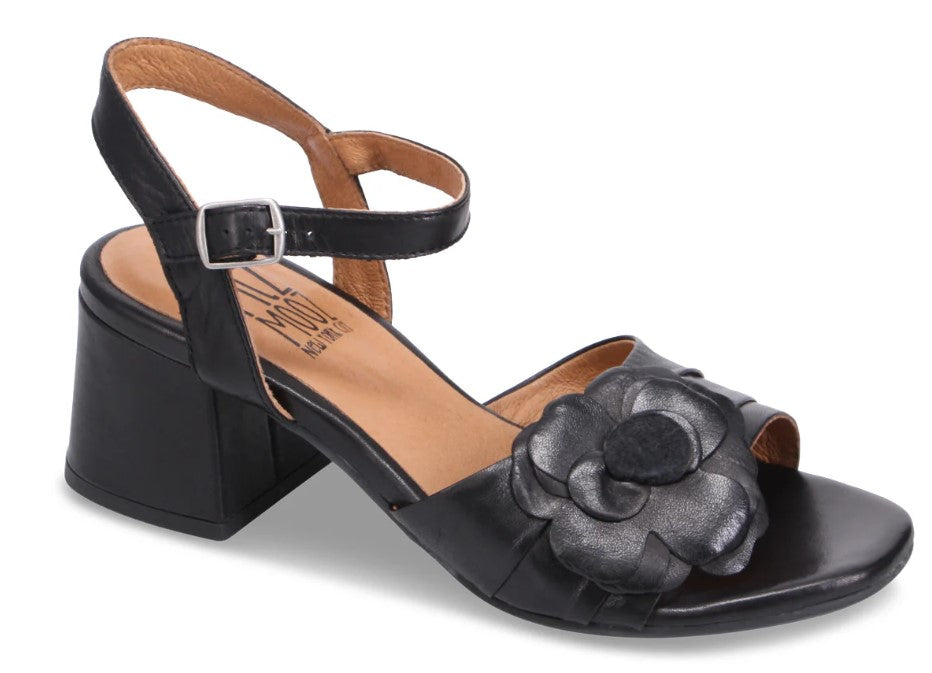 Black leather heeled sandal with an ankle strap and a floral accent.