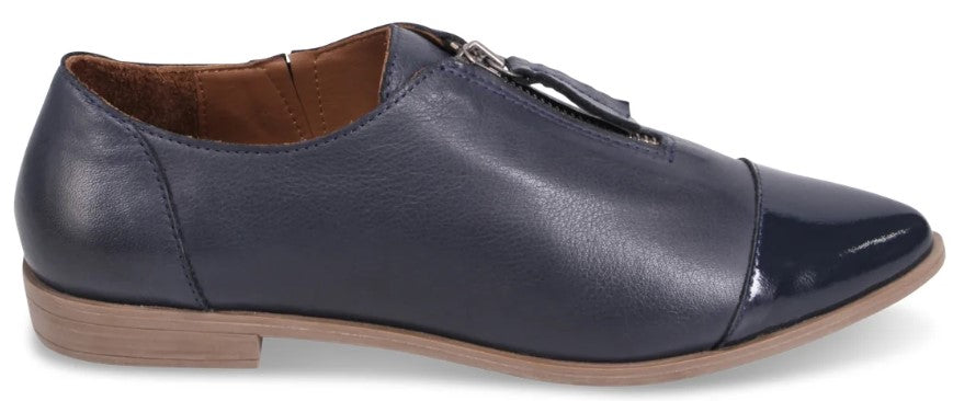 A dark blue leather flat shoe with a pointed toe, featuring a glossy patent leather toe cap and a zipper closure detail on the top.
