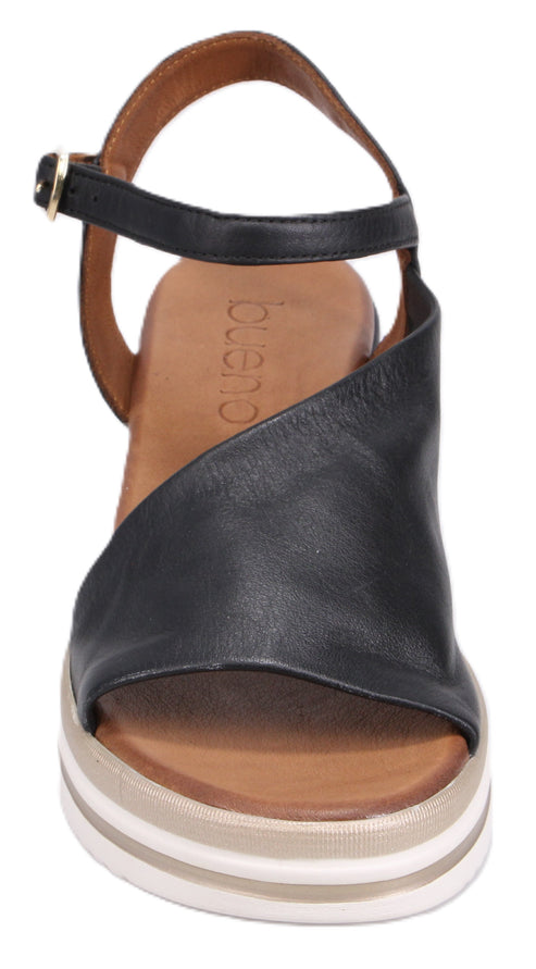 A black leather sandal with ankle strap and a platform sole with white stripes.