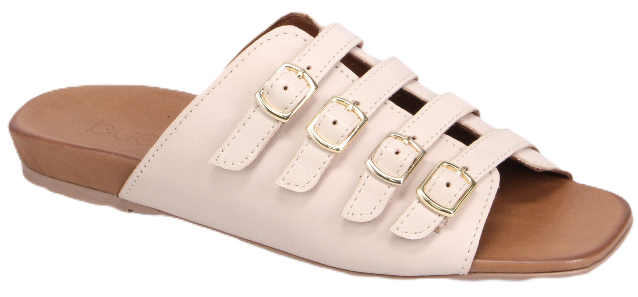 A sandal with a tan footbed and cream-colored straps that have three gold buckles.