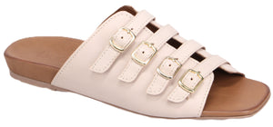A sandal with a tan footbed and cream-colored straps that have three gold buckles.