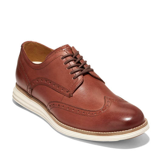 Brown leather oxford shoe with wingtip detail and brown laces on a white sole.