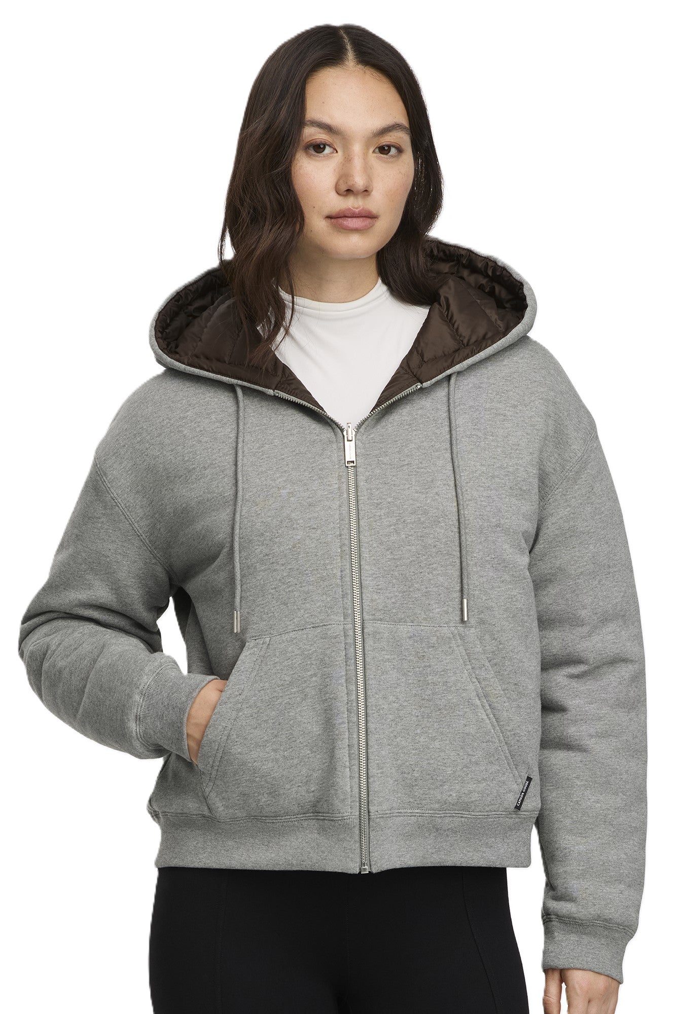 Woman in a gray, zip-up hooded sweatshirt with pockets.