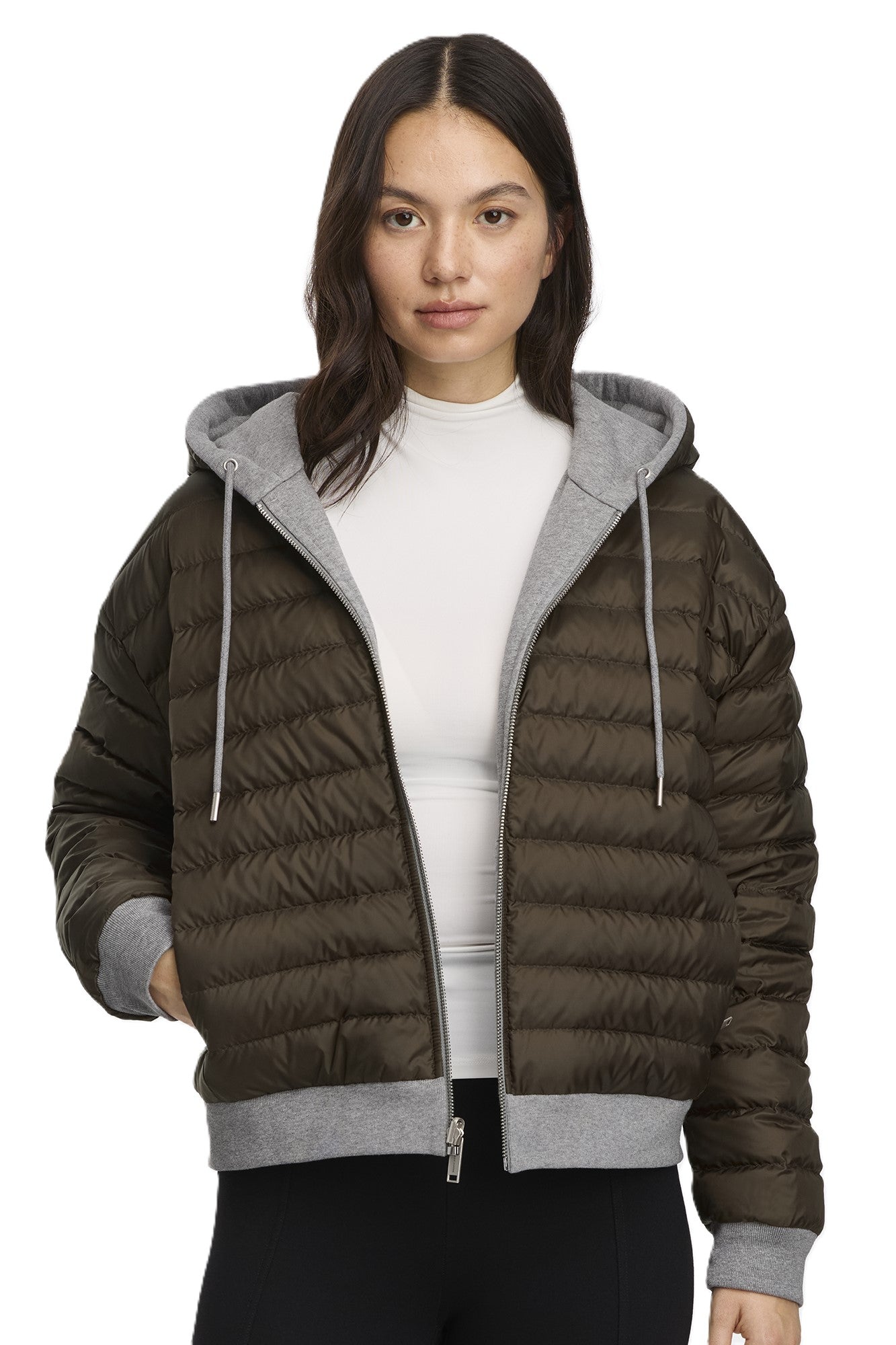 A woman wearing a short, olive-green puffer jacket with a light gray hood and trim.