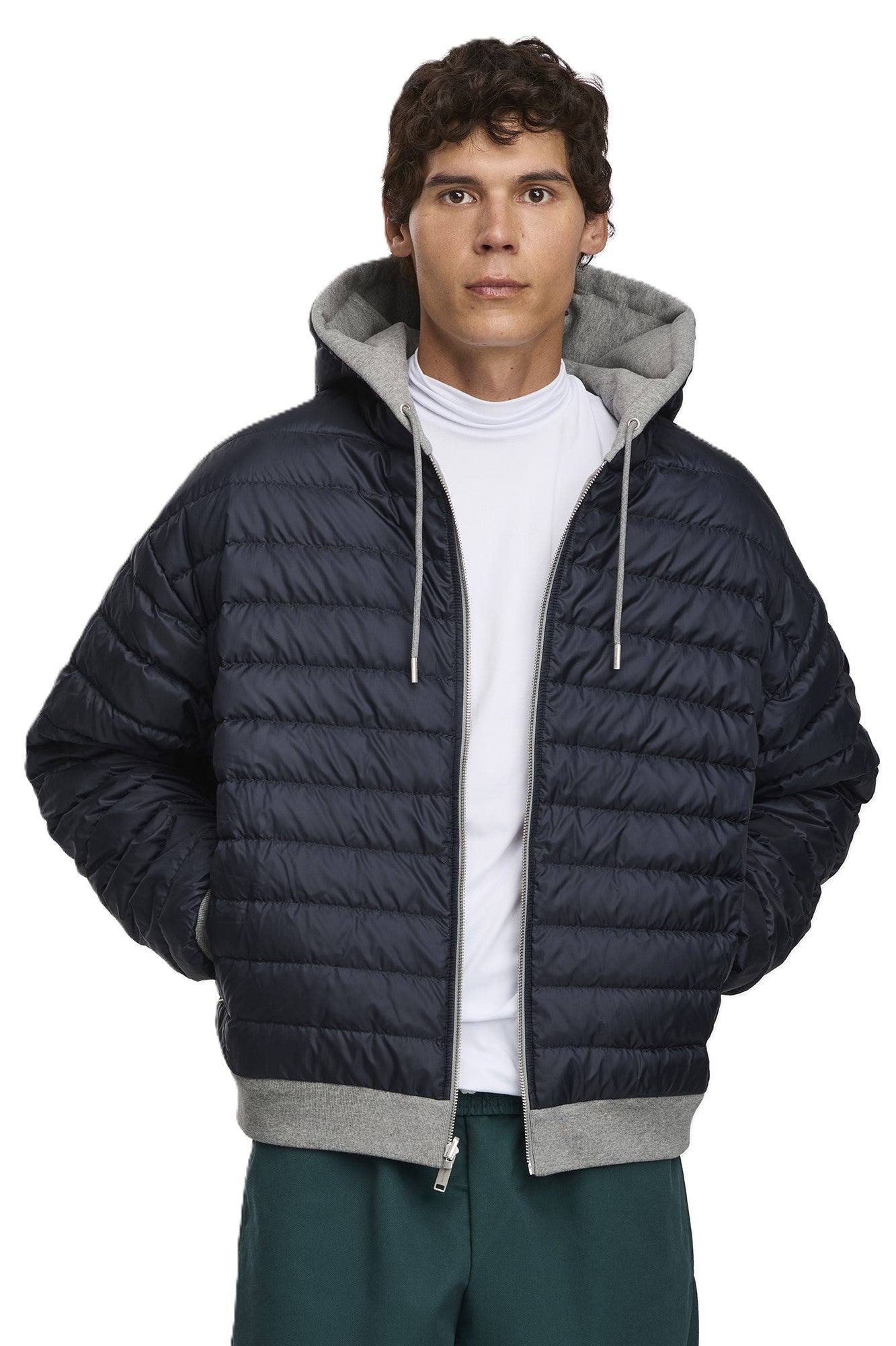 A man wears a navy blue hooded puffer jacket with gray accents and drawstring.