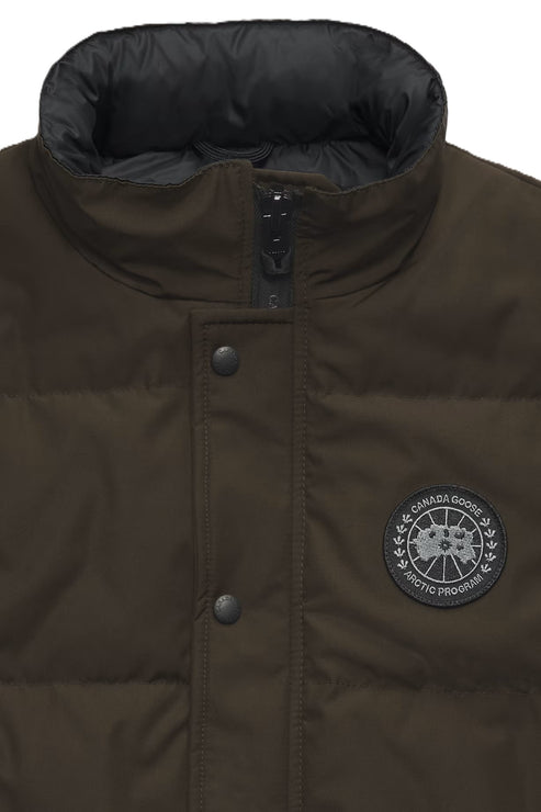 Close-up of a green puffer vest with a black collar and circular Arctic Program patch.