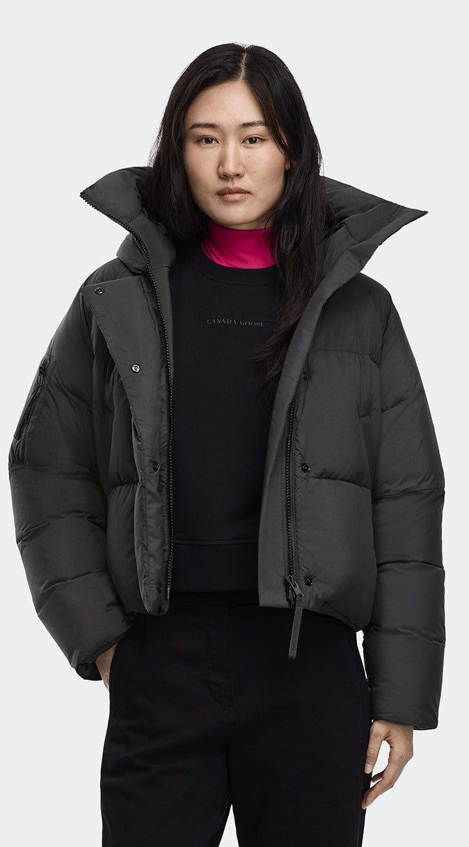 Woman wearing a black puffer jacket with a high collar over a black shirt with the text "calvin klein".
