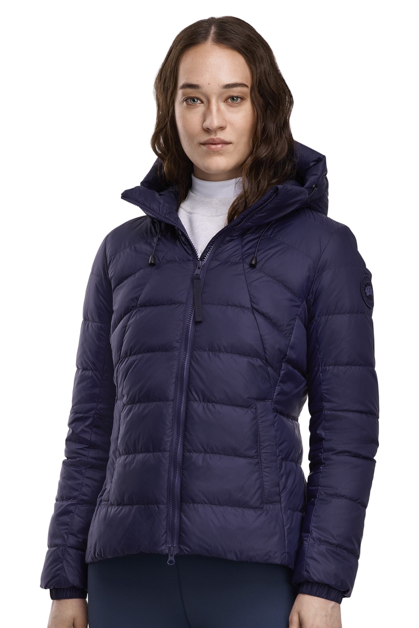 A woman wearing a navy blue, quilted puffer jacket with a hood.