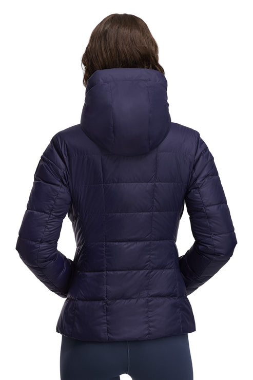 Back view of a woman wearing a quilted, hooded, navy blue jacket.